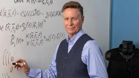 Paul Cheney Keith McElveen stands in front of a white board holding a marker pen