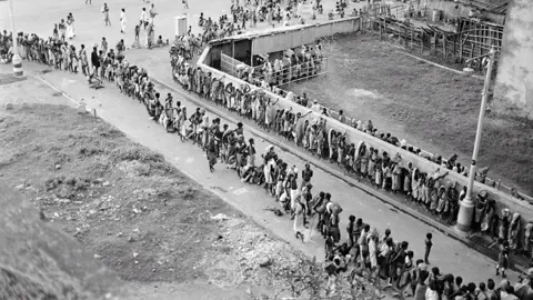 Getty Images Long queue for a soup kitchen winds round a street in Kolkata