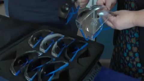 A black case full of what looks like safety googles with different areas blacked out or made to look hazy or misty. These replicate the range of vision a person might have with various eye conditions.