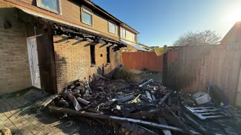 Steve Hubbard/BBC The rear of a house. Its yellow brickwork is charred black and some of the roof is crumbling. There is rubble and debris in the back garden.