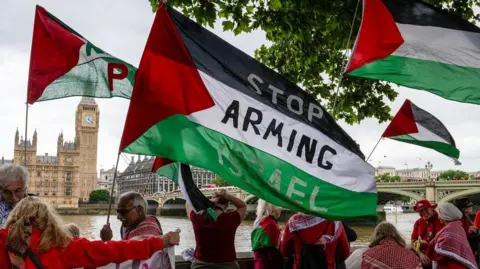 Protesters with Palestinian flags call for the UK to sanction Israel over the Gaza conflict, outside the Houses of Parliament
