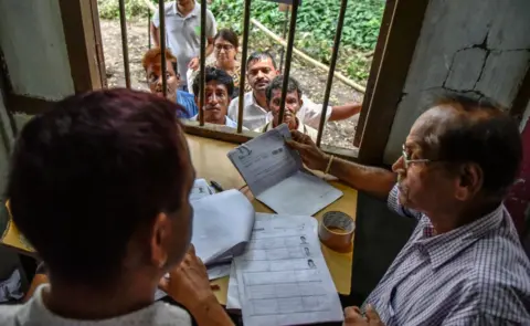 Getty Images People wait to check if their names are on the final list of proven citizens published earlier this month.