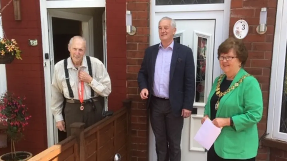 Burnley Council John Zelly receives his medal outside his house from Charlie Briggs and Anne Kelly