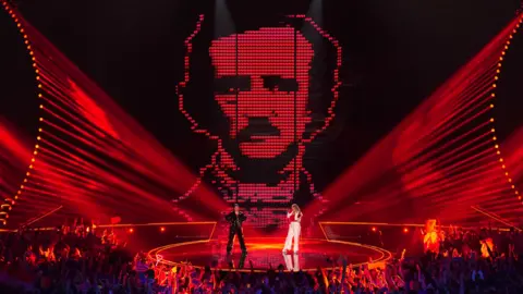 PA Media Austria's Teya & Salena in front of a giant picture of writer Edgar Allen Poe on a screen at Eurovision