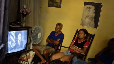 Getty Images A Cuban family watch at their home a live televised address by former President Jimmy Carter who speaks in Spanish to the Cuban people at the University of Havana on May 14, 2002 in Havana, Cuba.