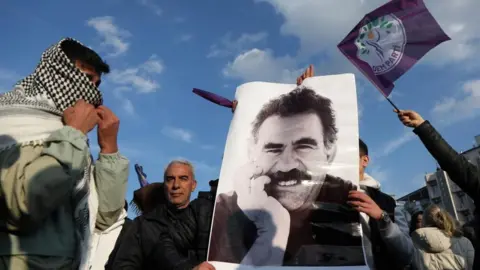 Reuters A demonstrator holds a picture of jailed Kurdish militant leader Abdullah Ocalan during a rally in Diyarbakir, while a man wearing a scarf looks on