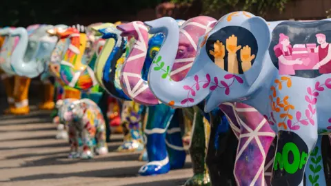 MOTE A line of painted elephant sculptures