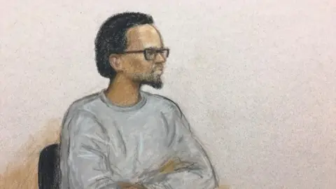 Julia Quenzler BBC Artist's sketch of a bearded man, wearing a grey round-necked top and glasses, sitting in a chair with arms folded