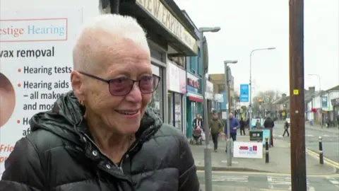 Woman in street in black coat and wearing glasses