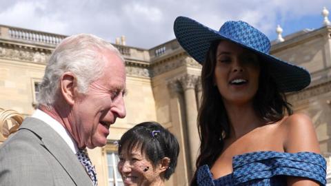 King Charles and Maya Jama smiling at Buckingham Palace
