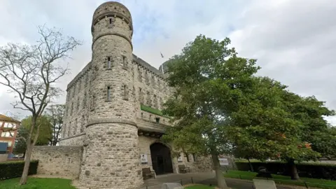 Google Street view of The Keep Military Museum. It is a large stone gatehouse, resembling a medieval castle with round turrets, crenulations and arrow slit windows.