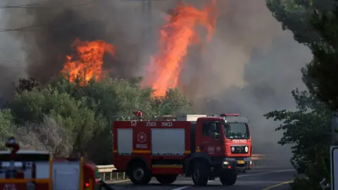 Firefighers try to extinguish a wildfire caused by projectiles launched by Hezbollah, ni Mevuot Hermon, upper Galilee, in northern Israel (4 July 2024)