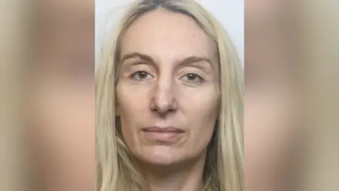 A custody mugshot of a woman with long blonde hair