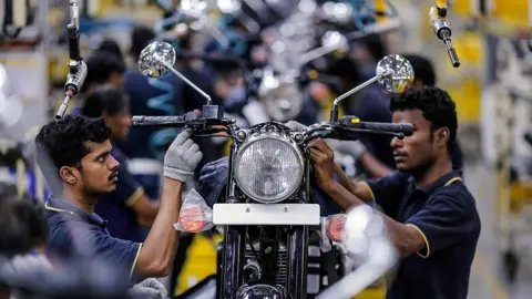 Getty Images Los empleados ensamblan motocicletas Royal Enfield Motors Ltd. Classic 350 en movimiento sobre una cinta transportadora en la línea de producción en las instalaciones de fabricación de la empresa en Chennai, India, el martes 14 de julio de 2015.