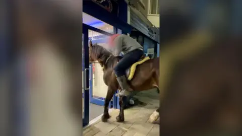 Man riding equine  done  doorway  to spot   shop