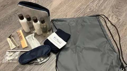 Sonal Mehta A kit is unpacked on the floor, including an eye mask, pen, comb, toothbrush and toothpaste, ear plugs and shower toiletries