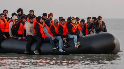  Migrants sit on a dinghy as they prepare to sail into the English Channel 