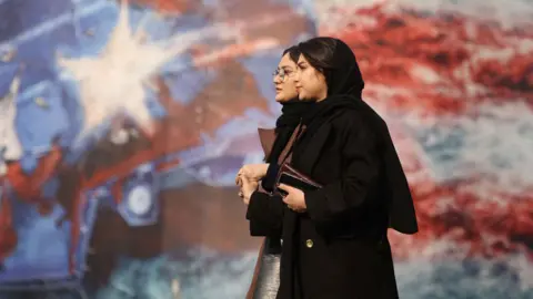 People walk past an anti-U.S. billboard in Tehran, Iran, January 26, 2026. 