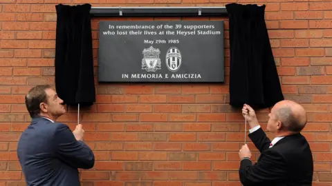 PA Media Two men unveil a memorial plaque at Anfield