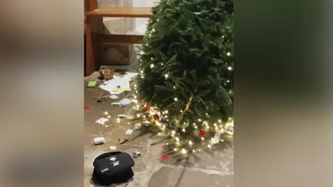 Contributed A Christmas trees lies horizontally on the floor of a church after it was torn down. A black first aid box sits next to it as well as decorations that have fallen off.