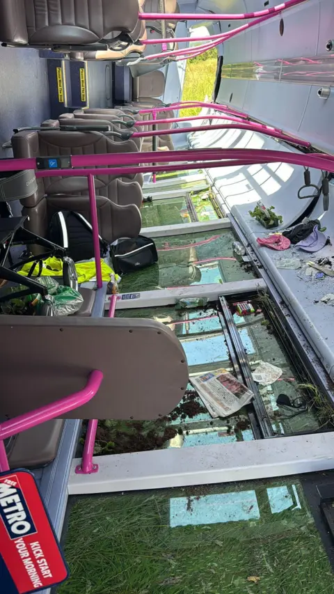 Martyn Pope The inside of the crashed bus. The bus is empty and there are disability walkers left as well as debris on the smashed windows.