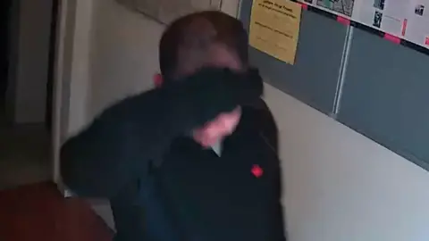 Cambridgeshire Constabulary Ismaili seen on CCTV in a black jumper, he is covering his face with his hand.