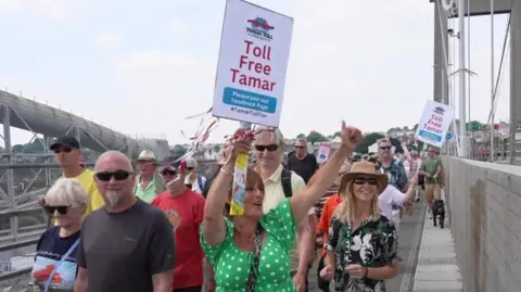 A wider view of the march showing a crowd of people stretching along the bridge.