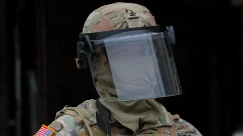 A National Guard member standing with a mask