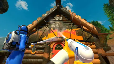 FuturLab An in-game screenshot from the video game PowerWash Simulator 2. We see a first-person perspective of the player using a pressure washer to spray water on a wooden house front which is very dirty. Another character dressed in blue cleaning gear is also spraying the house.