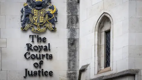 Getty Images Exterior of the Courts of Justice building, which holds the High Court and the Court of Appeal, in London. The wall bears a crest of black and gold.