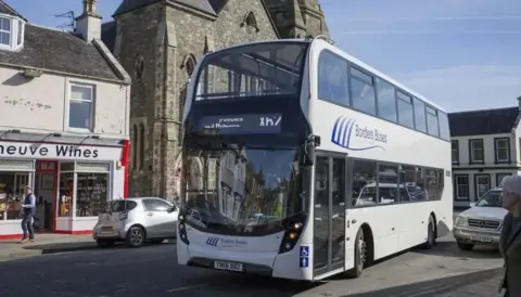 Borders Buses A white double decker passing through a busy street