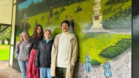 Mid Devon District Council Four artists stand in front of a new mural in the shelter at People's Park in Tiverton