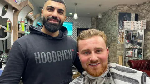 Elizabeth Baines / BBC Shirwan Mohammedi and Chad Hanakin in a barber shop