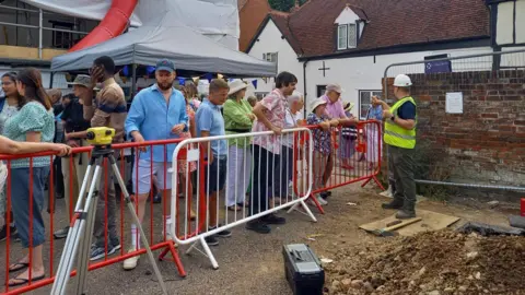 St Albans Museums A crowd of people are stood on the other side of a barrier, looking into the dig site