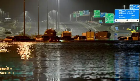 Giuseppe Cacace/AFP Vehicles are stranded in flood waters along a highway in Dubai