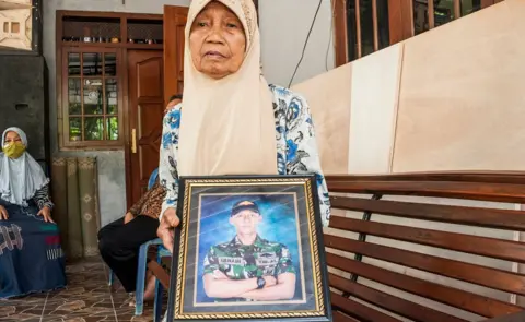 AFP Sarikem holds a photo of her grandson Gunadi Fajar Rahmanto at their home in Yogyakarta on April 26, 2021