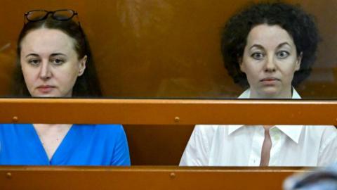 Yevgeniya Berkovich, right, and fellow playwright Svetlana Petriychuk sit behind a glass pane in court
