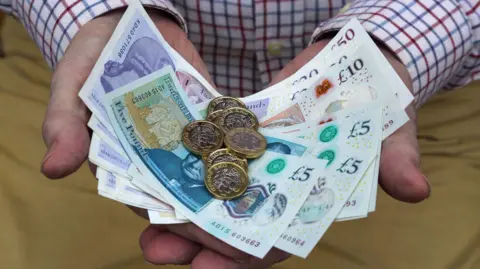 Getty Images A man holding cash in his hand