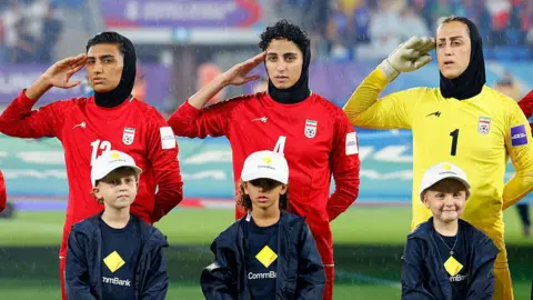 Iranian players, goalkeeper Raha Yazdani (R), Melika Motevalli (C) and Fatemeh Amineh, salute during the national anthem