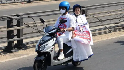 Getty Images West Bengal Chief Minister Mamata Banerjee rides pillion on an electric scooter to reach State Secretariat Nabanna to protest against fuel price hike.