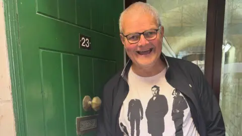 Supplied A man, Pete, smiles at the camera. He is standing in a doorway.