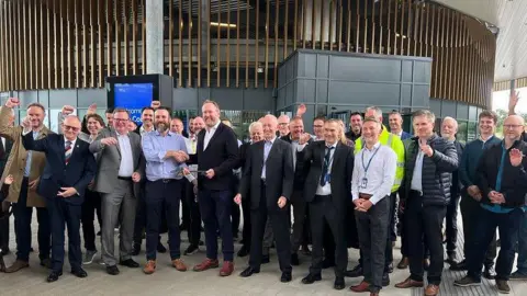 Gloucestershire County Council A large group of men cheering in front of the new transport hub