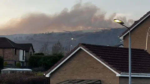 A hill on fire with houses in the foreground