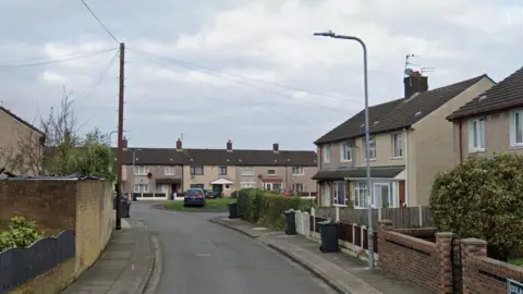 A small cul de sac of semi detached houses with a green area in the middle.