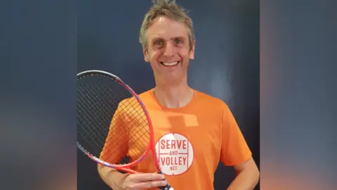 Rob Salmon Rob Salmon, wearing an orange t-shirt and holding tennis racket