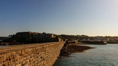 Getty Images A view of St Peter Port in Guernsey, showing a harbour wall, the sea and housing in the background.