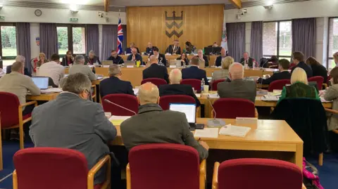 A group of councillors sat in a council chamber. 