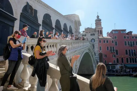 Manuel Silvestri / REUTERS A rally of people stand on the Rialto bridge in Venice