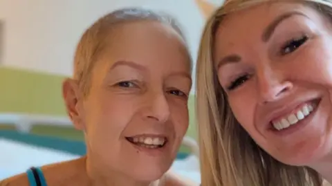 Rebecca Evans A selfie of Rebecca and Jella in a hospital room. They are both smiling. Jella wears a black and blue tank top.
