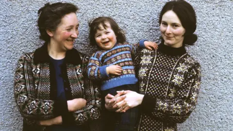 Chris Morphet Two women and a young girl pose wearing Fair Isle sweaters in Lerwick, Shetland Islands in 1970.